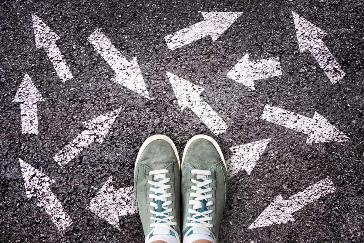 A person in sneakers with chalk drawn arrows pointing in multiple directions.